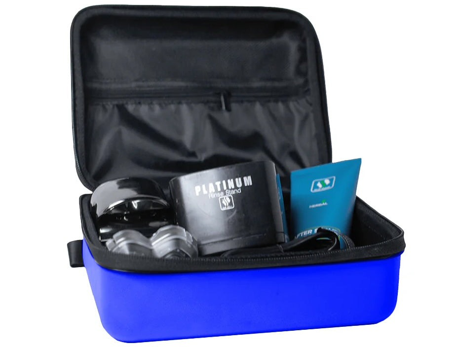 An open blue Pitbull Deluxe Travel Case displaying its organized interior. The case contains a variety of grooming accessories, including a Pitbull Platinum rinse stand, a blue aftershave bottle, and a compact shaver. The inner lid has a black zippered pocket for additional storage. The case combines practicality with style, offering a sleek solution for carrying grooming essentials.
