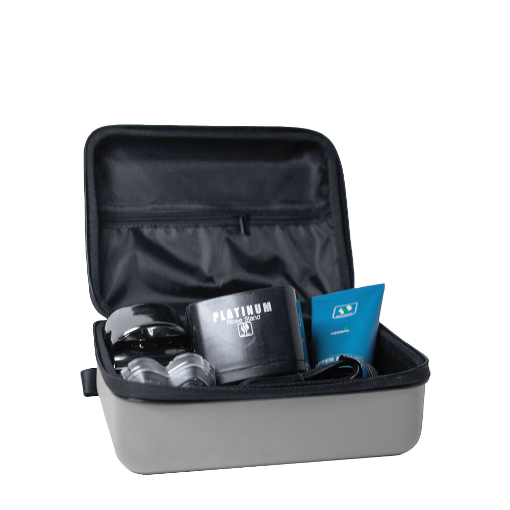 An open Pitbull Deluxe Travel Case with a black interior, holding various grooming items including a “Platinum Rinse Stand,” a blue after-shave cream tube, and additional accessories. The case features a spacious compartment and a mesh pocket in the lid for organized storage.
