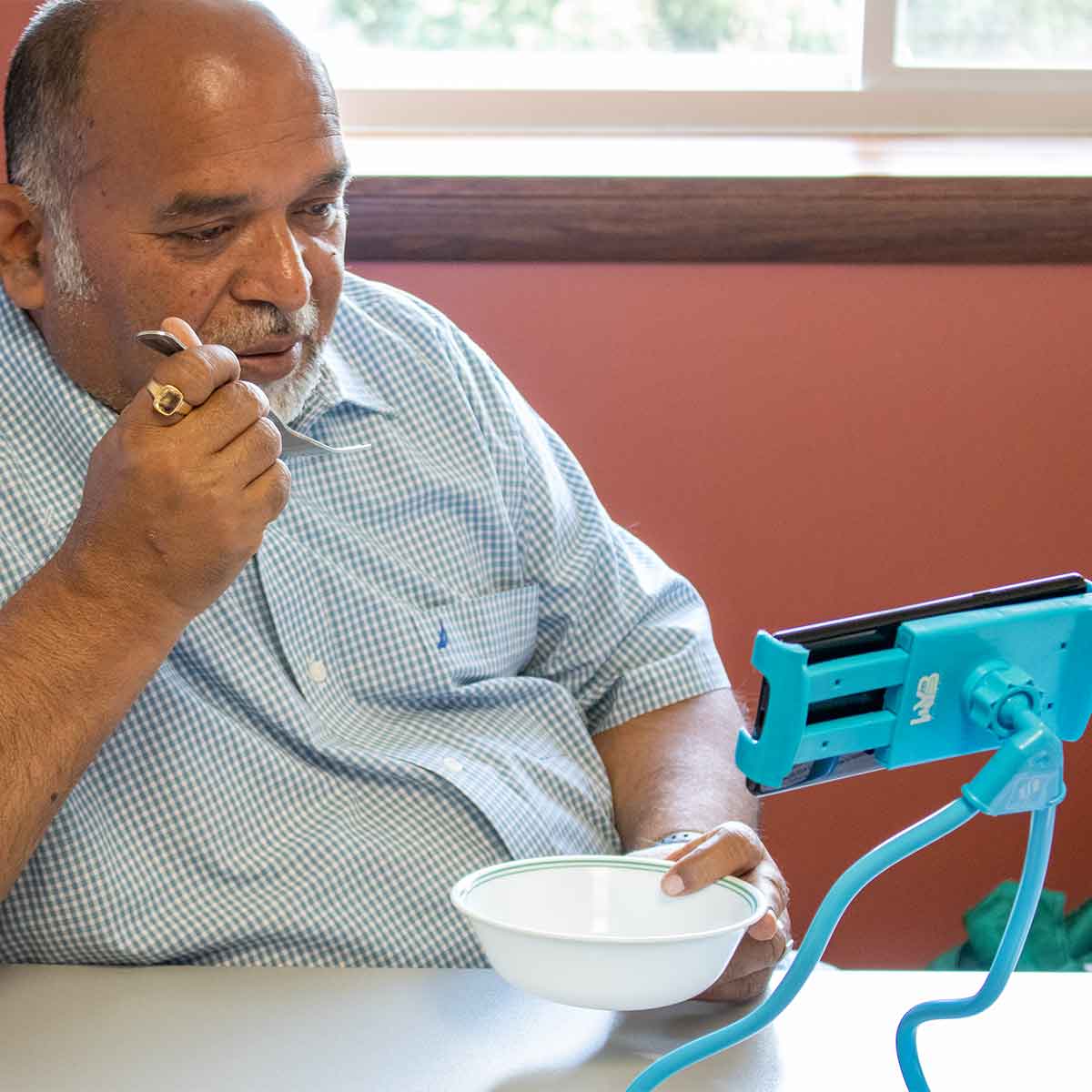 A man using Phone holder while eating food 