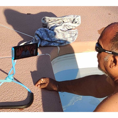 A man using watch your Back phone holder to watch videos as a stand on ground